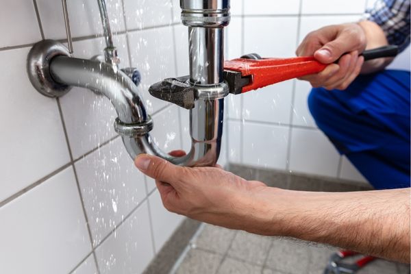 plumber fixing leaking pipe