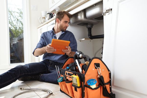 plumber diagnosing leaking pipe