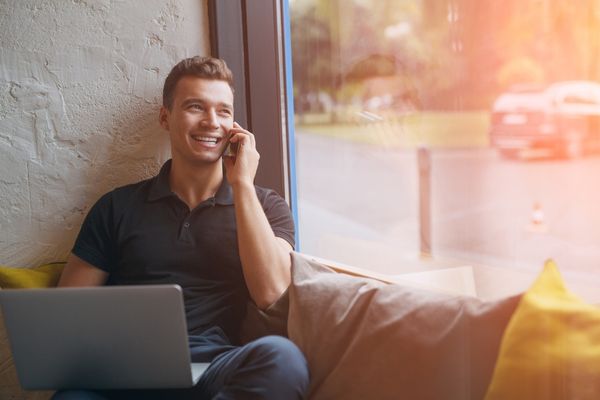 happy man using phone and laptop