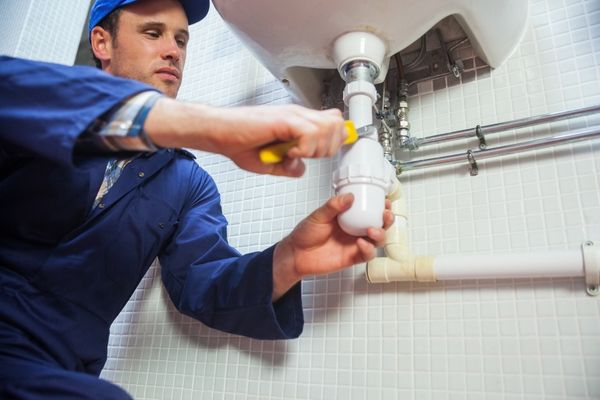plumber fixing piping in bathroom